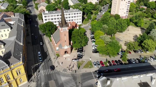 Descending drone shot looking over a church build of bricks by a cross road