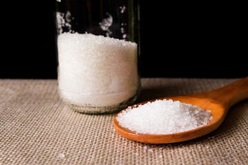 close up image of salt on the wooden spoon. selective focus. visible noise due to high ISO.