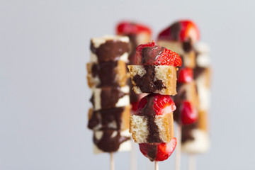 Fruit and cake skewers with melted chocolate