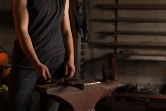 Female metalsmith holding tool in factory