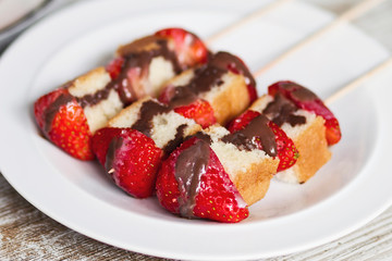 Fruit and cake skewers with melted chocolate