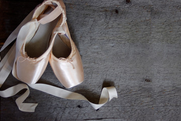 New pink ballet Pointe shoes on rustic wood  background with copy space
