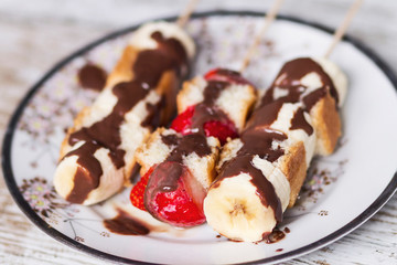 Fruit and cake skewers with melted chocolate
