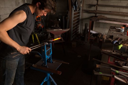Female metalsmith shaping horseshoe in factory - Powered by Adobe