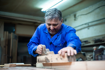 carpenter working in workshop, a worker planing a tree with a planer