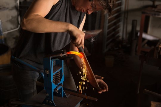 Female metalsmith shaping horseshoe in factory - Powered by Adobe