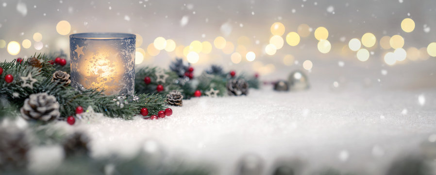 Dekoration für Weihnachten mit Kerze, Lichtern und Tannenzweigen auf Schnee