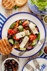 Greek salad. Traditional Greek salad consisting of fresh vegetables such as tomatoes, cucumbers, peppers, onions, oregano and olive oil, top view. A delicious vegetarian, mediterranean dish