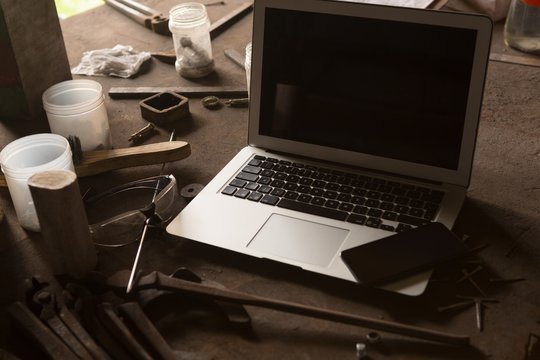 Laptop and mobile phone in metalsmith factory