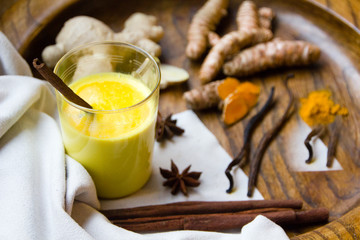 Golden almond milk with fresh and organic curcuma, ginger and decorated with cinnamon and vanilla. Trendy Asian drink suitable for vegans with many health benefits. Selective focus
