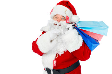 santa claus in red costume with sale tags holding shopping bags and showing silence gesture isolated on white