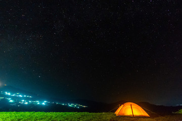 Fototapeta na wymiar Orange tent glows under night sky.