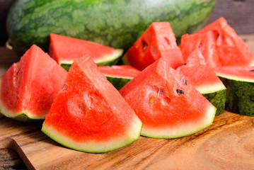 whole and portion cut watermelon on wooden cutting board