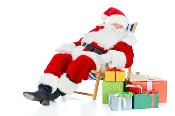 santa claus relaxing on beach chair with christmas presents on white