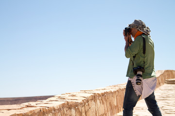 Photographer on the background of blue clear sky on a clay wall in the Berber city. Africa Morocco Ait Ben Haddou