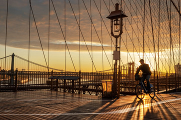Bicyclist on Brooklyn Bridge during sunrise in New York. USA
