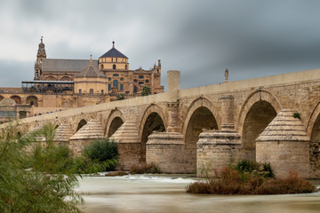 Fototapeta premium Long exposure photography of Mosque-Cathedral and the Roman Bridge in Cordoba with cloudy sky, Andalusia, Spain