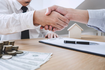 Real estate broker agent and customer shaking hands after signing contract documents for ownership realty purchase, Concept mortgage loan approval