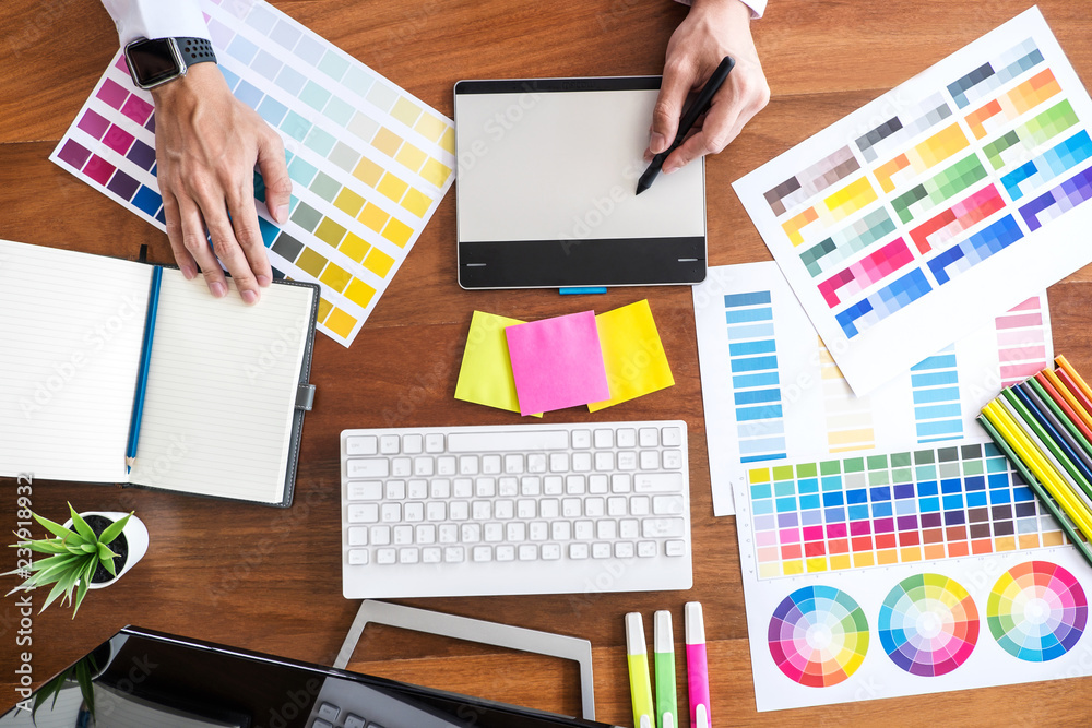 Aufkleber Image of male creative graphic designer working on color selection and drawing on graphics tablet at workplace with work tools and accessories, top view