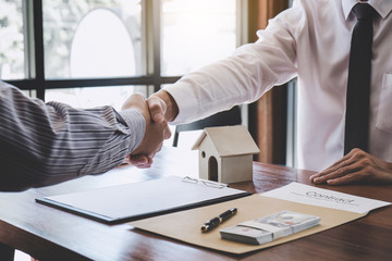 Real estate broker agent and customer shaking hands after signing contract documents for realty purchase, Bank employees congratulate, Concept mortgage loan approval