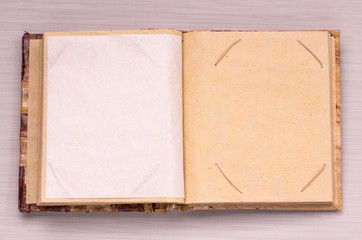Open old book on textile background. Old photo-book with blank yellow stained pages from handmade paper. Background for text, photo and recipes. Book cover from dried leaves.