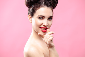 Beauty portrait of young brunette woman on a bright pink background. Model with make-up and hairstyle, closeup, fashion glamour photo