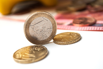 closeup of  yellow piggy bank on euro coins and bank notes on white background