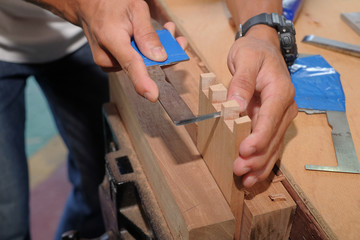 Skilled joiner working in carpentry. Amateur woodworker making dovetail join for wooden drawer in carpenters workshop