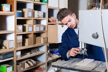 guy using ribbon saw to cut plank at workshop