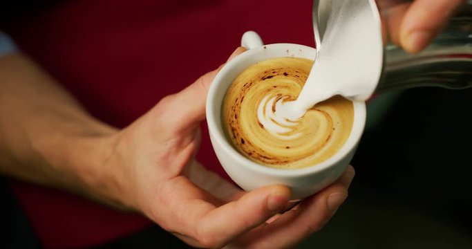 Macro of a barman while drawing with the froth the cappuccino in a typical italian bar.
