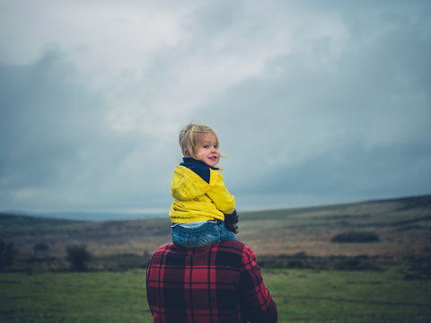 Toddler riding on father's shoulders on the moor