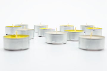 A set of white and yellow tealight paraffin candle lies on a white background with a clipping path.