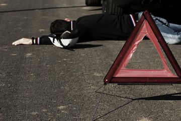 The man lies on the road behind the black car next to the bicycle helmet.The car collided...