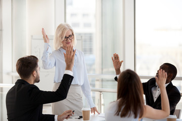 Smiling mature female mentor hold educational training for diverse employees, mixed workers raise...