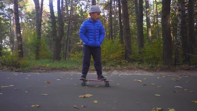 Child on skateboard boy ride on skate outdoor in autumn park