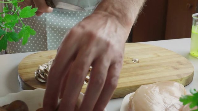 Cutting mushrooms on cutting board for preparing chicken marsala