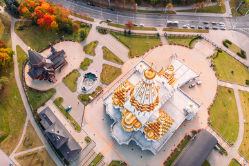 Top view temple Golden domes, landscape design, autumn trees red-yellow foliage and roadway nearby. Minsk Republic of Belarus.