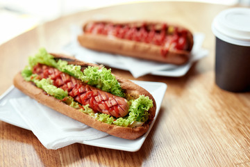 Tea or coffee and delicious hot dogs in a fresh bun with ketchup and mustard and lettuce