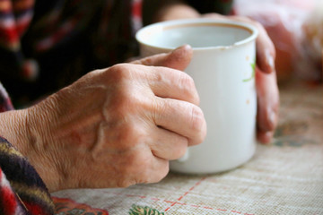 hands of an elderly woman holding a Cup of tea 