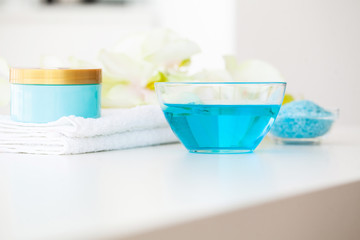 Organic Blue Sea Salt. Spa Composition With Cream, Salt, Towel and Flowers On a White Background. Wellness Products and Cosmetics