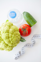 Diet. Fitness and healthy food diet concept. Balanced diet with vegetables. Fresh green vegetables, measuring tape on white background. Closeup