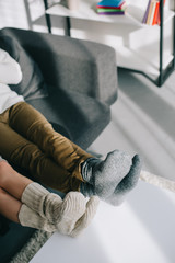 cropped shot of couple in woolen socks relaxing on couch at home