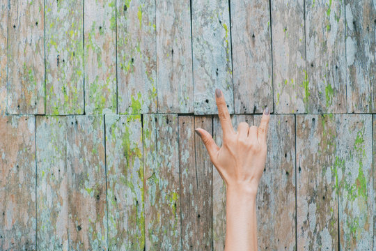 Woman hand showing I Love You sign by fingers. Old wooden background.