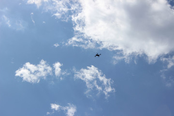 Naklejka na ściany i meble Drone uav flying surveillance security spy hobby recording background small far motion center clear blue noon sky clouds