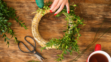 Unrecognisable woman making christmas wreath in living room. DIY Christmas decoration concept....