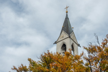 Turm einer Friedhofskapelle hinter herbstlichen Bäumen in Kirchheim unter Teck