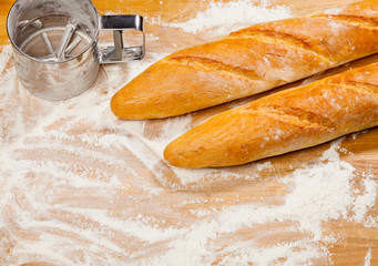 Artisanal French baguettes and flour sieve or sifter on a table