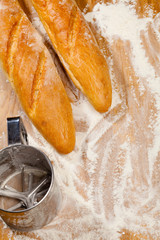 Artisanal French baguettes and flour sieve or sifter on a table