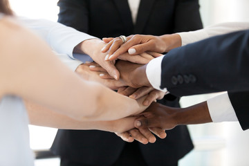 Close up of diverse employees stack hands in pile show mutual support, multiethnic workers promise loyalty and help involved in team building activity, team united at motivational business training - obrazy, fototapety, plakaty