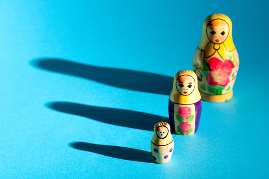 Row of nesting dolls with hard shadows on background